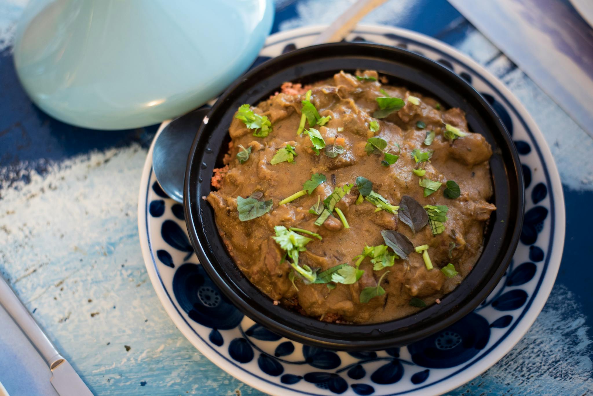 A savory Moroccan tagine garnished with fresh herbs, served in a traditional dish.